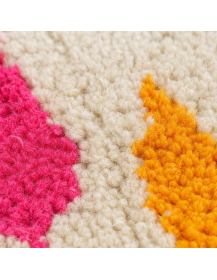 Détail des fibres laineuses et des motifs géométriques multicolores du tapis