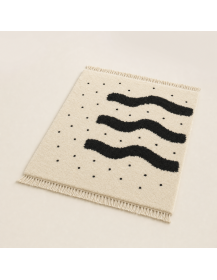 Vue en perspective du tapis Rive Blanche montrant le champ écru, les bandes noires irrégulières et la texture du poil