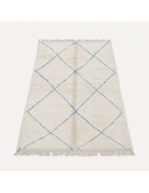 Vue en perspective d’un tapis artisanal marocain en laine ivoire écru avec treillis de losanges bleu gris pâle
