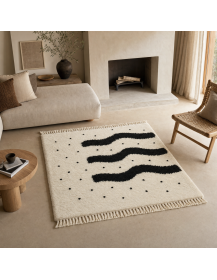 Mise en scène salon contemporain : tapis écru et noir devant canapé, bois clair et accessoires écrus