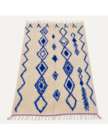 Vue en perspective d’un tapis berbère en laine écrue à losanges bleu cobalt et franges artisanales