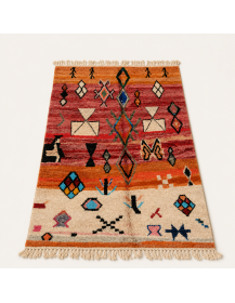 Vue en perspective d’un tapis berbère artisanal marocain en laine aux motifs géométriques polychromes