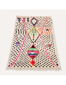 Vue en perspective d’un tapis berbère artisanal en laine avec motifs noirs, roses et multicolores