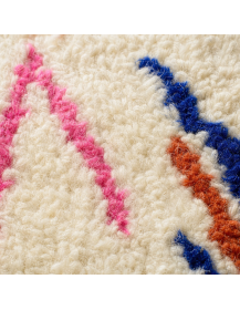 Détail de la texture dense et moelleuse de la laine du tapis ivoire multicolore