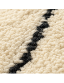 Détail de la texture fibreuse et moelleuse de la laine écrue avec motif noir charbon irrégulier