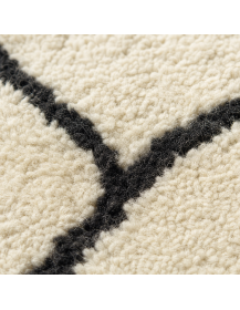 Détail de la laine dense et légèrement fibreuse d’un tapis artisanal marocain ivoire et charbon