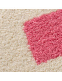 Détail de la texture bouclée et duveteuse de la laine d’un tapis ivoire à motif rose vif