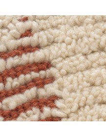 Détail du poil bouclé en laine ivoire et des lignes terracotta du tapis artisanal marocain