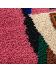 Détail de la laine bouclée et dense d’un tapis marocain artisanal rose magenta aux motifs géométriques