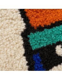 Détail de la texture bouclée et touffetée de la laine du tapis écru multicolore
