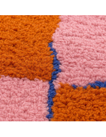 Détail du poil dense et bouclé en laine d’un tapis artisanal marocain orange terre cuite et rose poudré