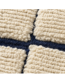 Détail de la texture laineuse nervurée et du relief des panneaux écrus du tapis