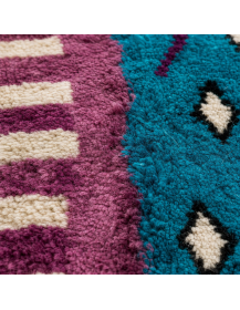 Gros plan sur la texture dense et veloutée de la laine du tapis marocain turquoise et prune