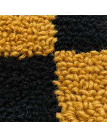 Détail macro des fibres de laine et du relief tufté jaune moutarde sur fond noir