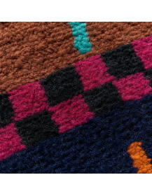 Gros plan sur la texture dense et irrégulière de la laine, les stries horizontales et les motifs géométriques colorés