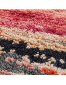 Détail de la texture fibreuse en laine et des bandes horizontales irrégulières du tapis rose poudré