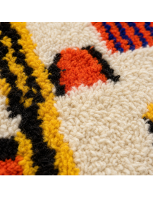 Gros plan sur les fibres de laine bouclées et les motifs colorés irréguliers du tapis