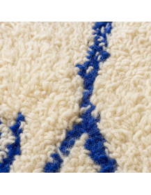 Détail macro du poil shaggy en laine et des motifs linéaires bleu cobalt du tapis artisanal marocain