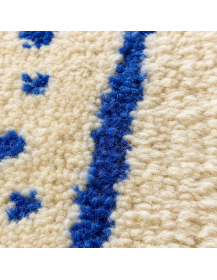 Détail de la texture en laine du tapis ivoire crème, motifs bleu cobalt et fibres irrégulières