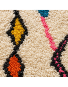 Détail de la texture bouclée et moelleuse de la laine d’un tapis marocain aux motifs géométriques colorés