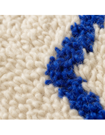 Détail de la laine épaisse et bouclée avec motifs bleu cobalt aux contours légèrement irréguliers